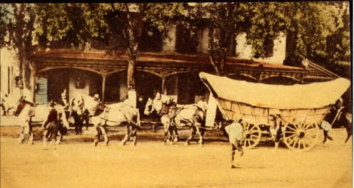 Vintage hand tinted postcard of a wagon parked outside the Old Four Mile Inn & Tavern on the National Road.
