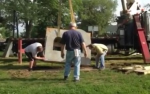 Volunteers work together to install the 4,000 pound concrete letter at Westgate Park.